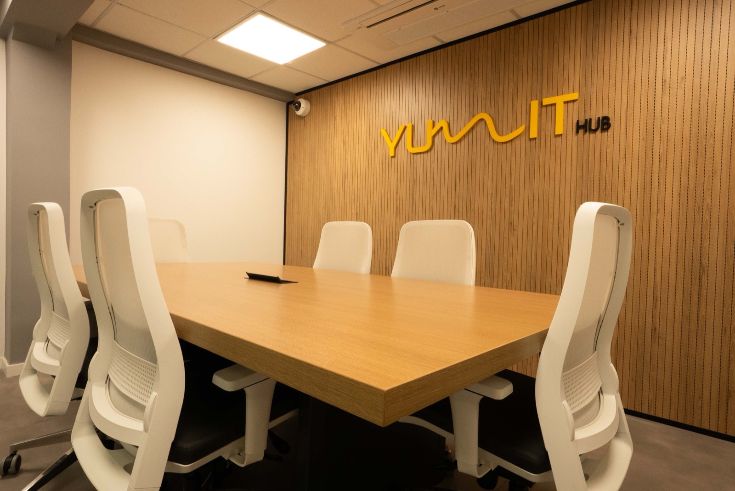 Sala de Reunião para 7 pessoas do Yumit Hub — ambiente compacto com TV, microfone Shure e marca Yumit ao fundo